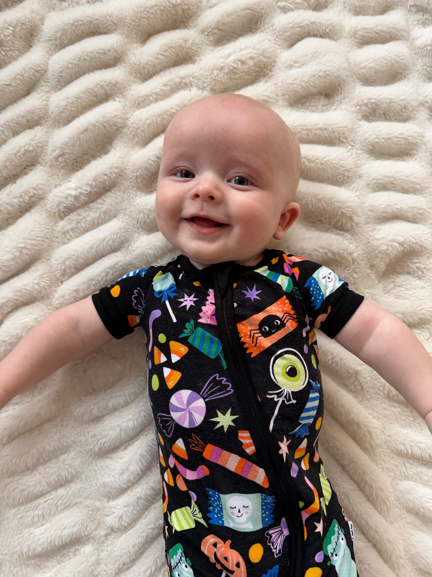 Baby London smiling in his Halloween candy-print onesie