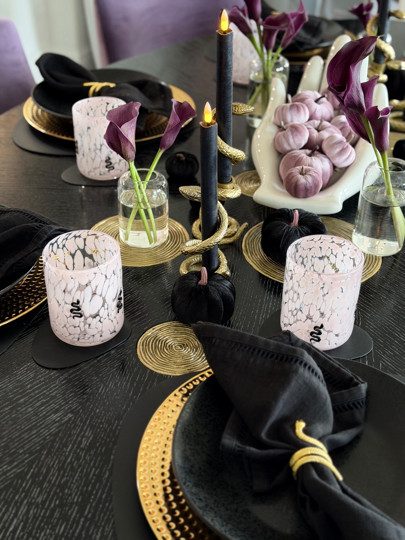 Tablescape detail with gold snake candle holders, black tapers, calla lilies and the pink marbled snake glasses