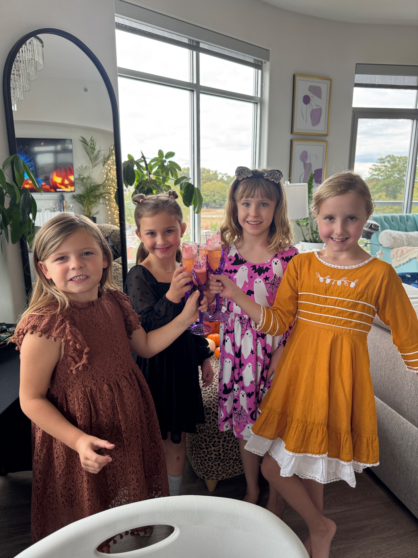 Four girls toasting with purple goblets; Lily in a pink ghost dress and jeweled cat ears