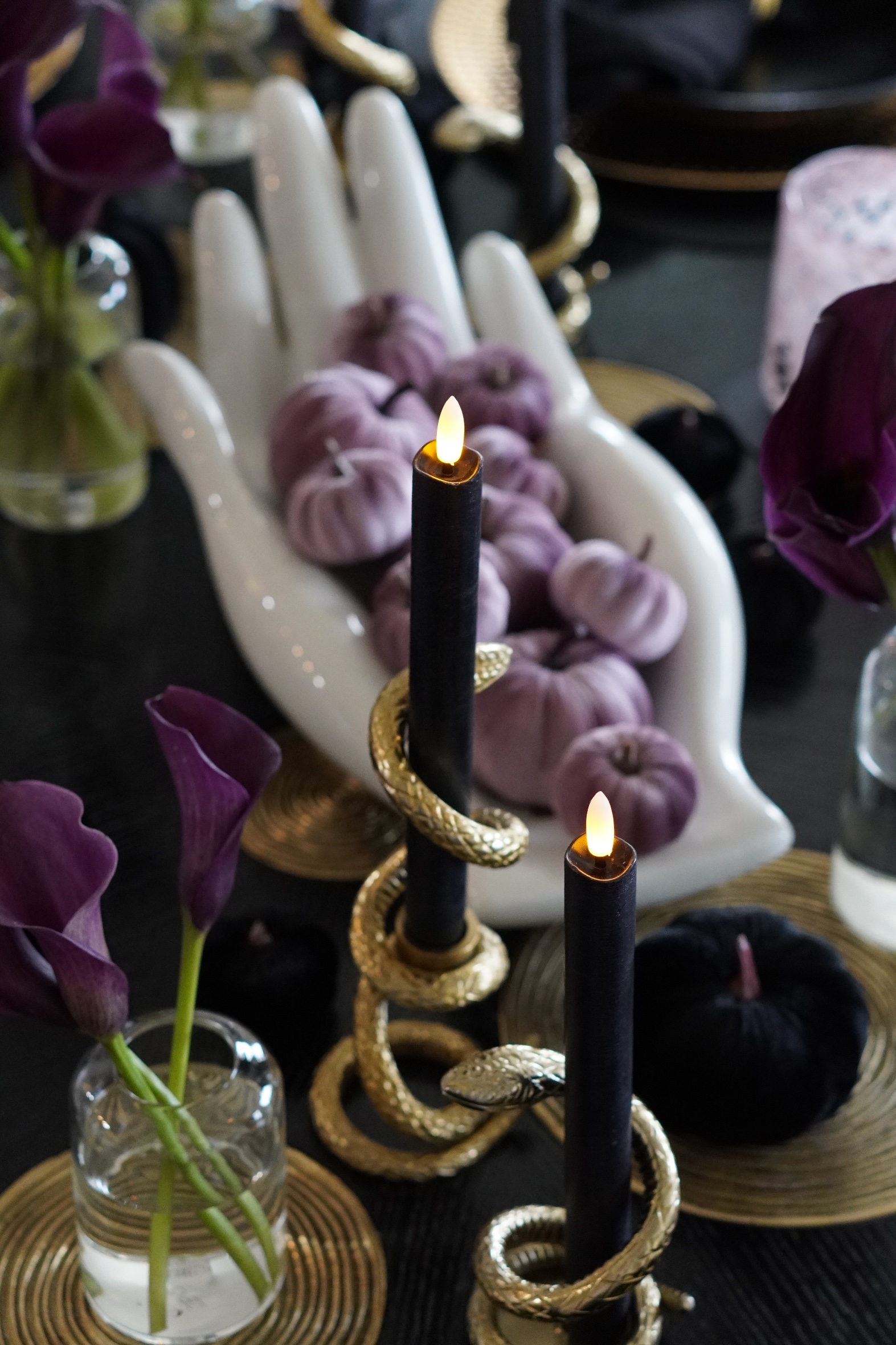 Jonathan Adler Gilded Eve hand bowl filled with lilac velvet pumpkins, with gold snake candle holders and purple calla lilies