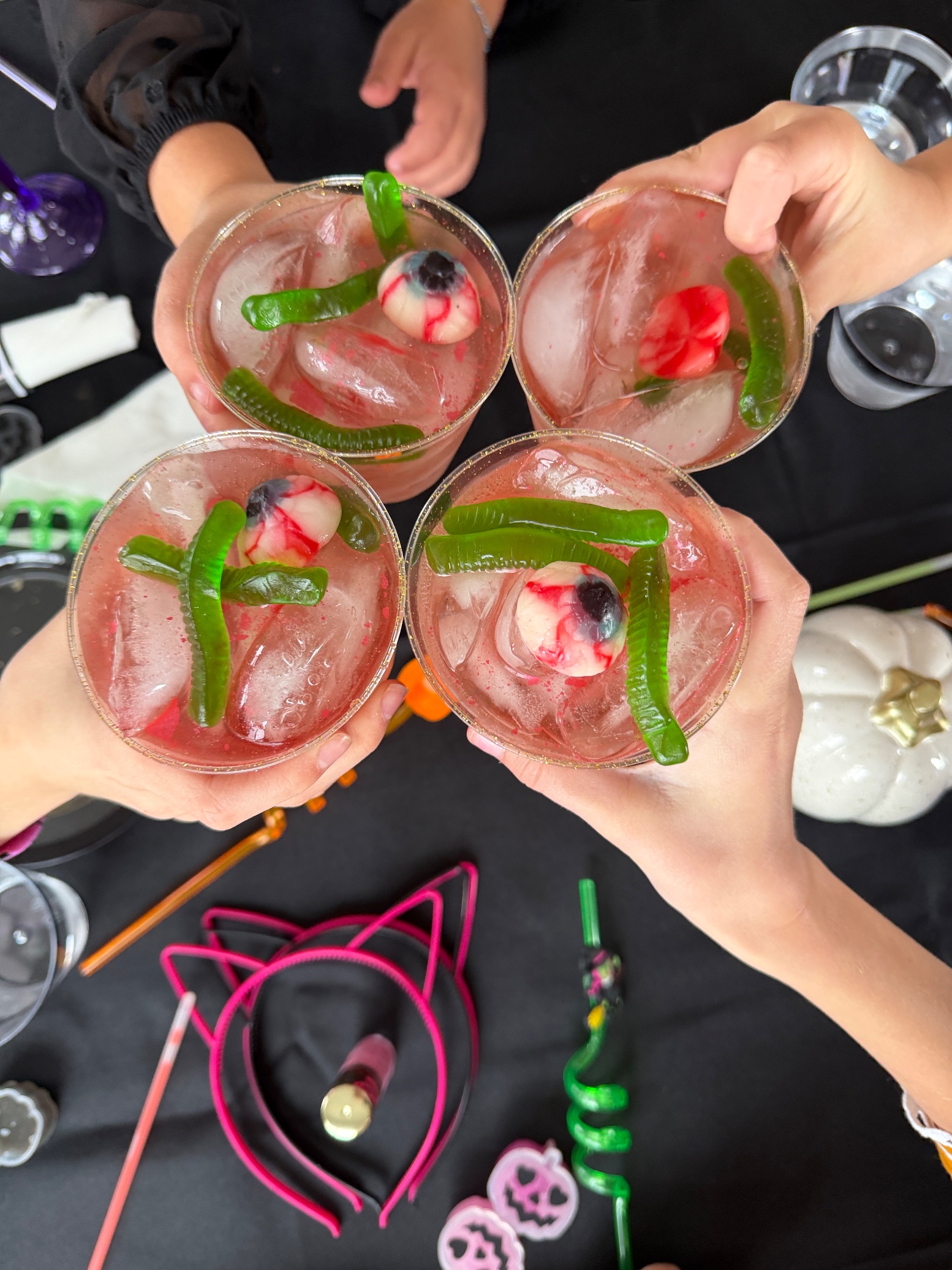 Kids' pink Shirley Temples with gummy eyeballs and gummy worms, seen from above