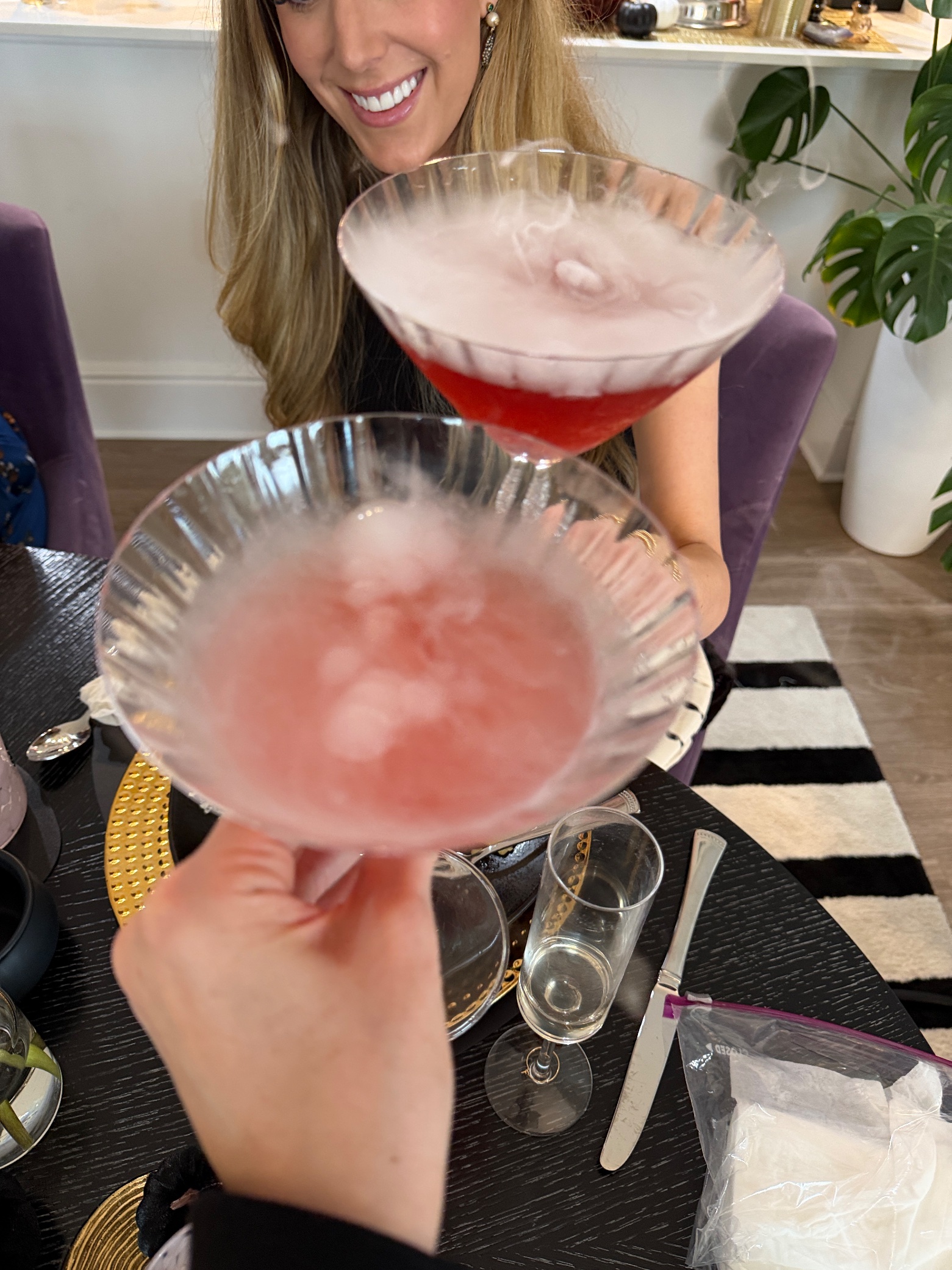Two smoking pink martinis being toasted with dry ice