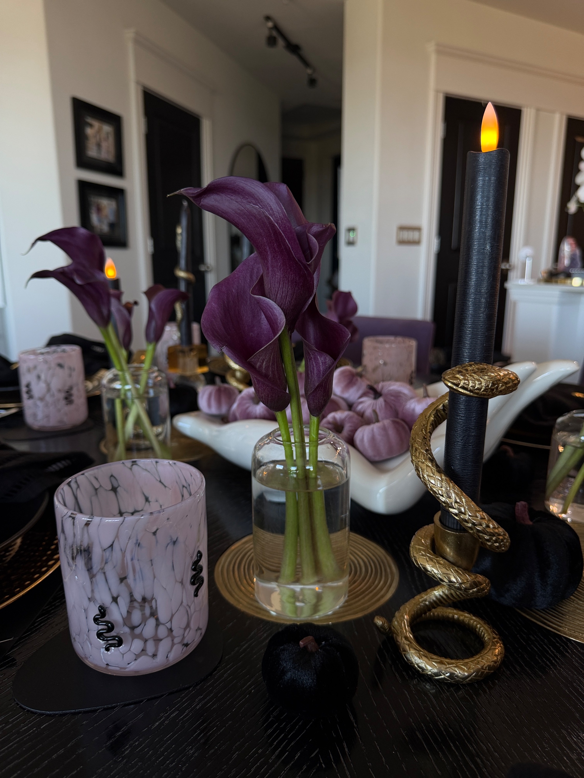 Tablescape close-up with purple calla lilies, a gold snake candle holder and a pink marbled snake glass