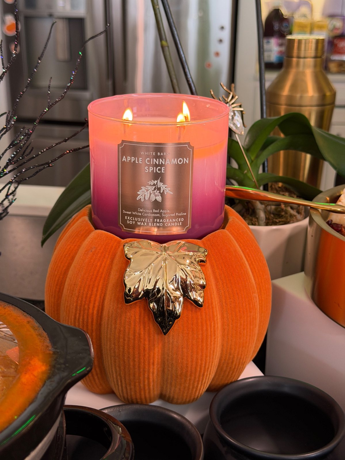 The Apple Cinnamon Spice candle burning on the orange velvet pumpkin