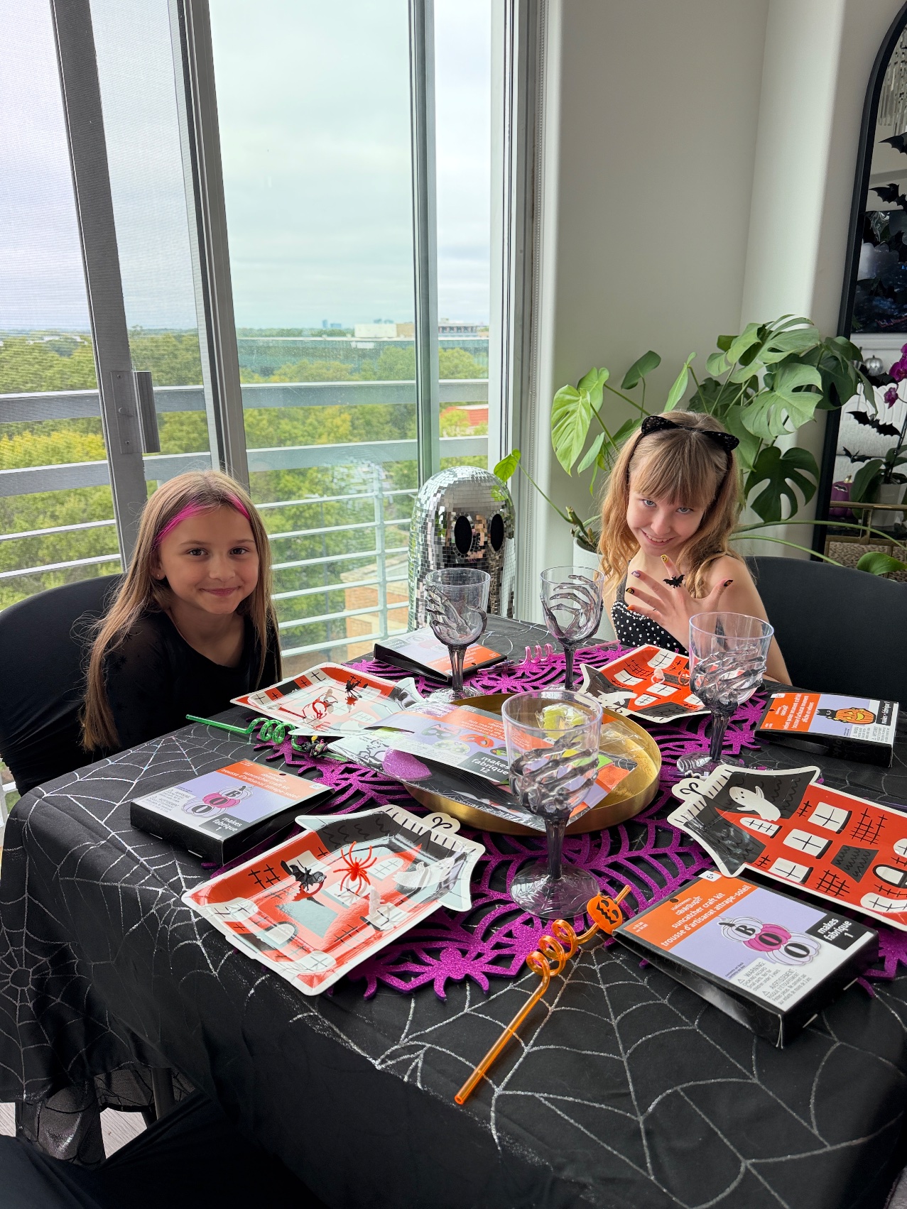 The kids' Galloween table with haunted house plates, skeleton hand goblets and craft kits, Lily and her friend