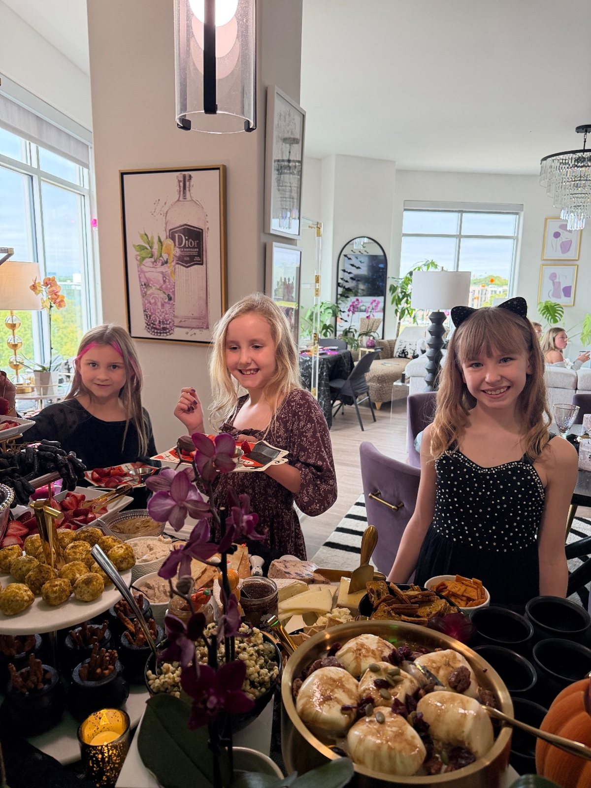 Lily and her friends at the grazing table, burrata and mini cheese balls in front of them