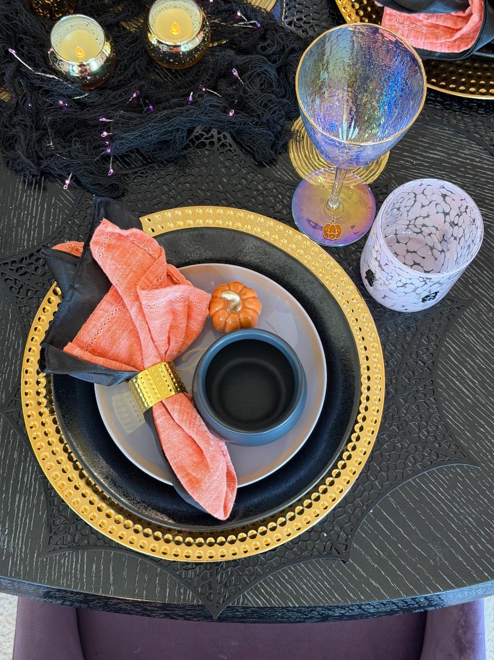 Place setting with a mini black cauldron bowl on the plate, an iridescent goblet and the pink snake glass